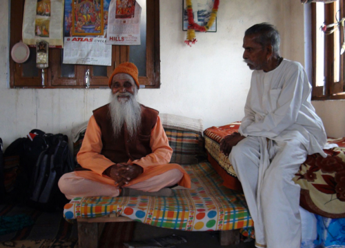 Father Varma sitting with Paramananda Puri Maharaj in his kitchen